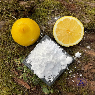 citic acid powder with two halves of lemon on a ,ossy log