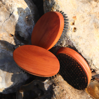 Wood and bristle oval military hairbrushes on rocks showing different views