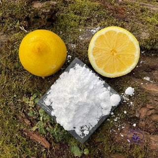 Citric acid with lemon halves on mossy log