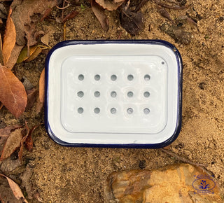 Enamel soap dish on sand with leaves